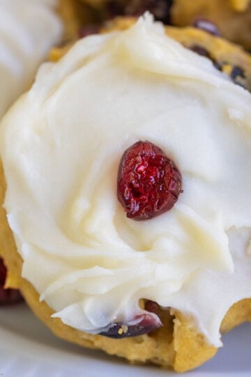 Pumpkin cranberry cookies and cream cheese icing with a single cranberry in the middle.