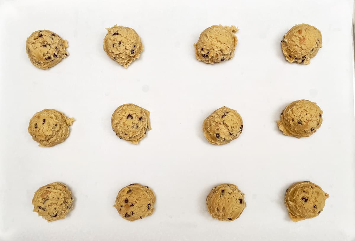 Twelve cookie scoops of chocolate toffee cookies.