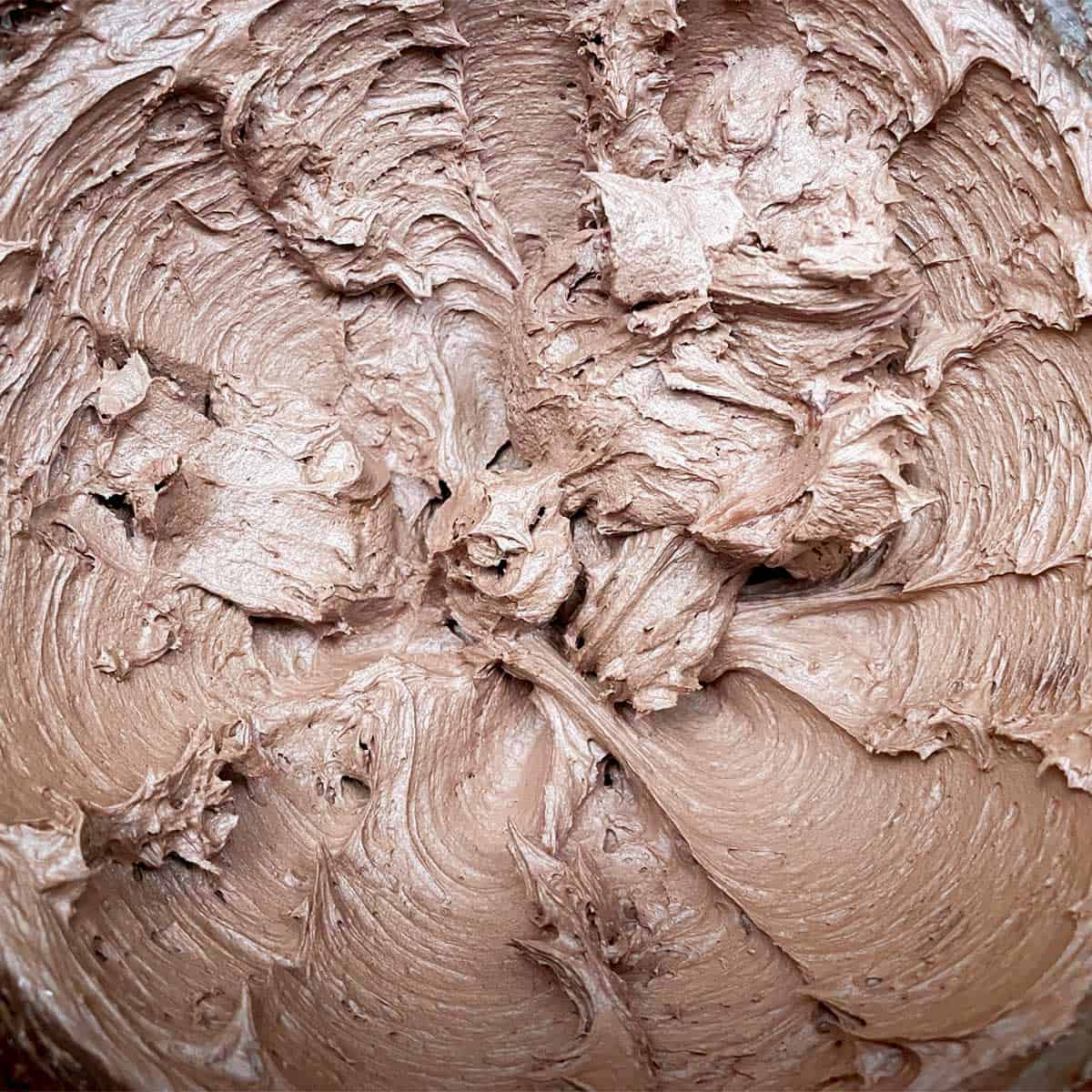 Creamy whipped chocolate icing in a mixer bowl.