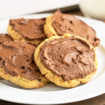 A white plate with five peanut butter cookies with chocolate icing.