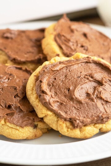 A white plate with five peanut butter cookies with chocolate icing.