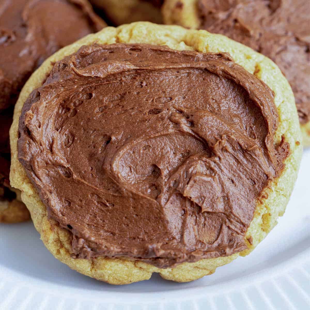 Front view of a peanut butter cookie with chocolate icing on a white plate.