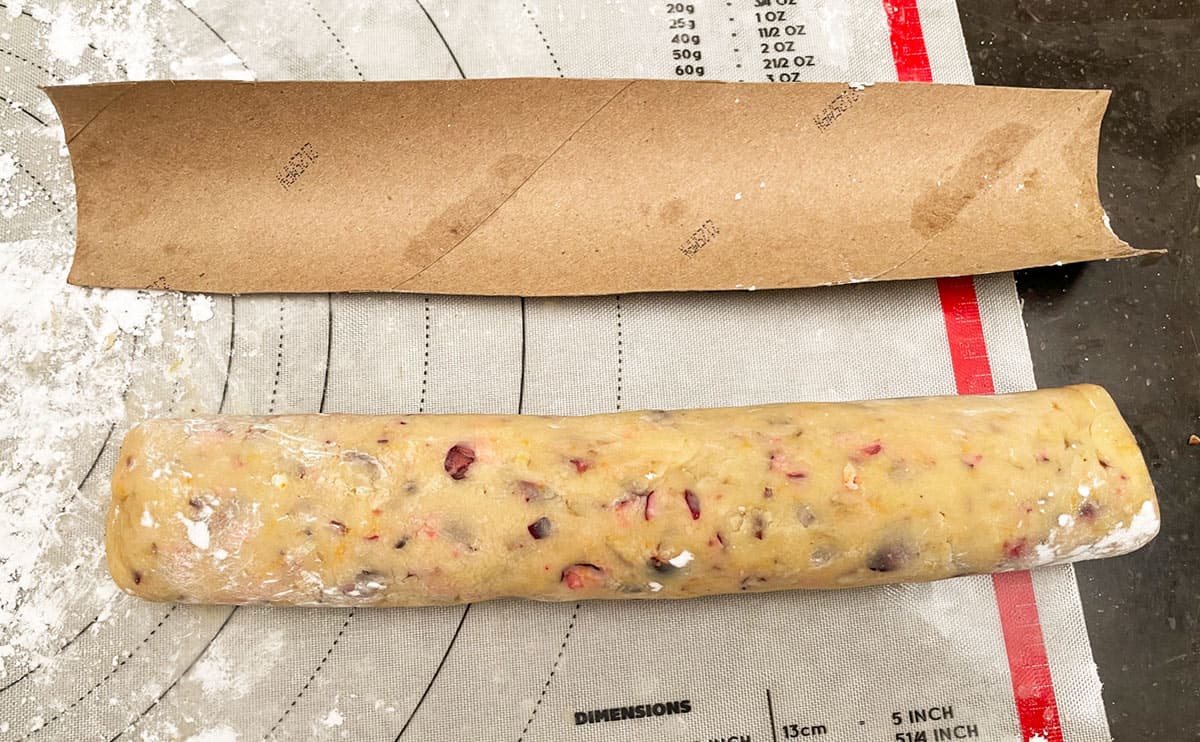 Rolled cookie dough log with a half cardboard tube to cradle the log in the refrigerator.