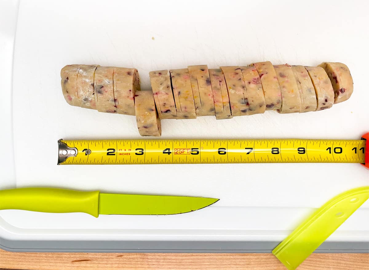 Slicing a cookie log ½ inch thick to be baked, based on a measuring tape.