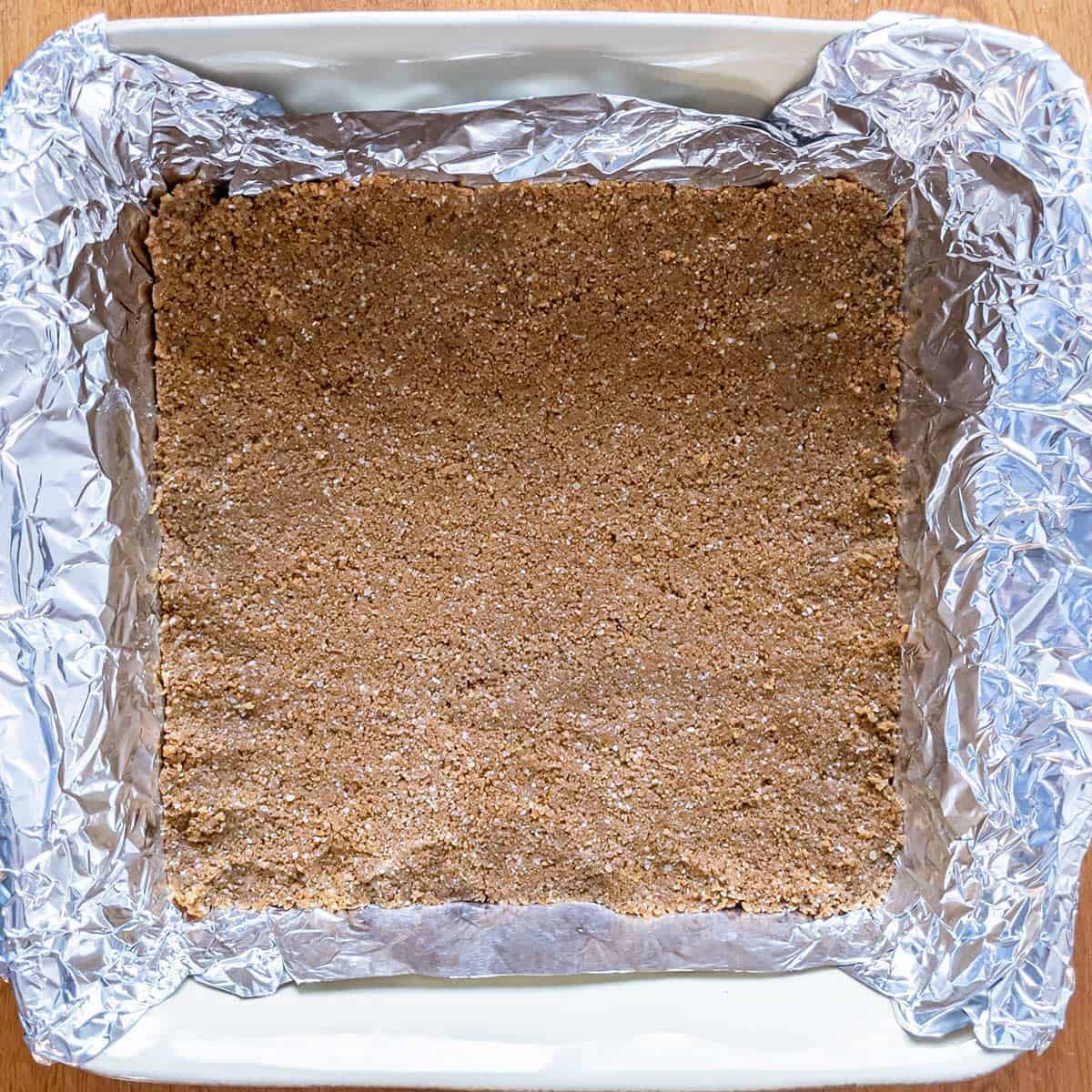 Graham cracker crust pressed onto the tin-foiled lined baking dish.