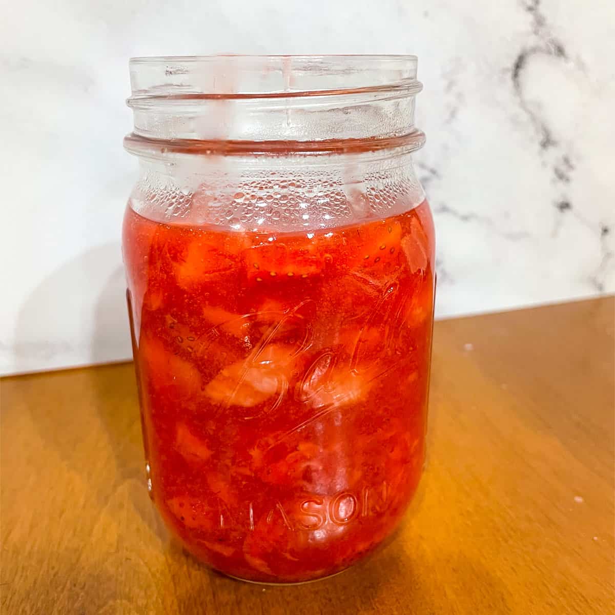 Finished strawberries topping cooling in a mason jar.