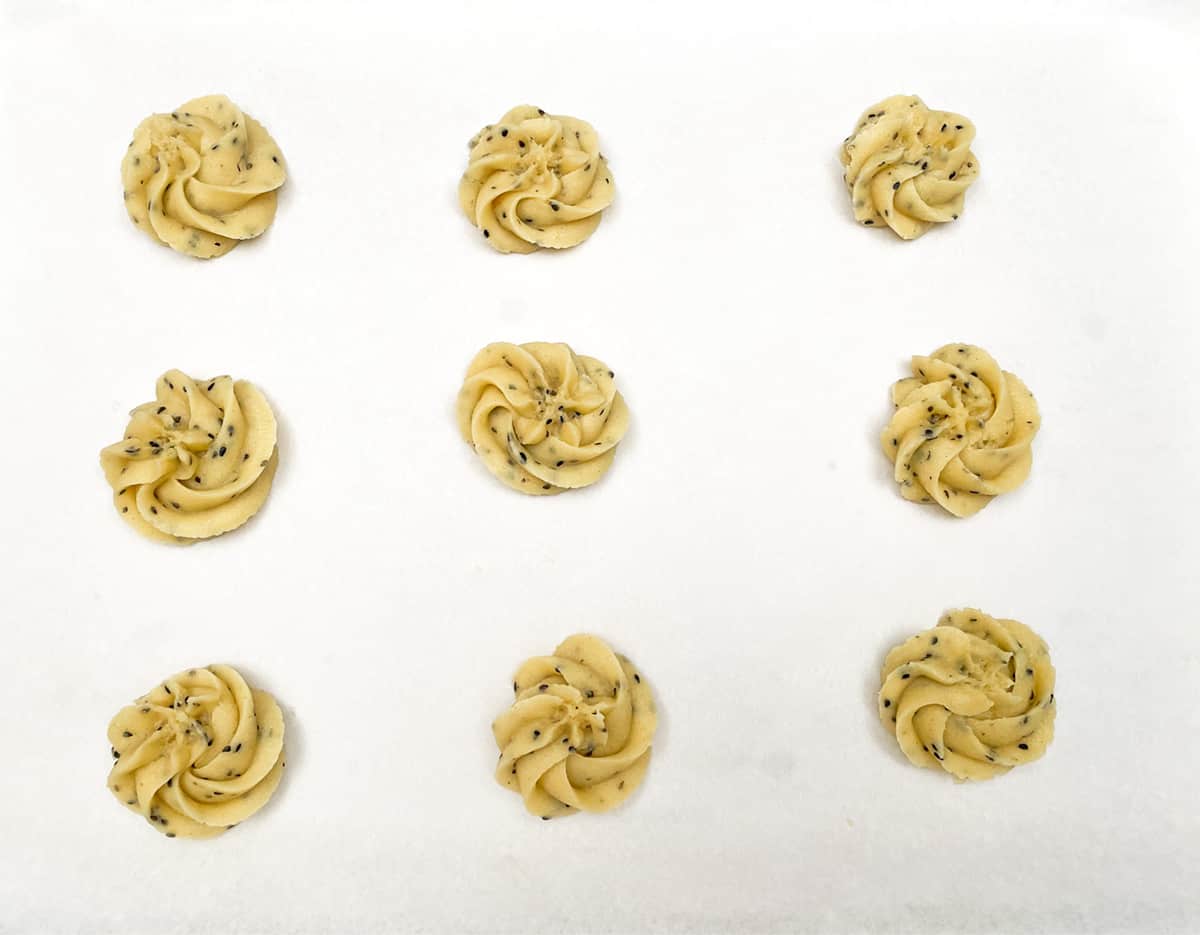 Piped swirl black sesame butter cookies on a piece of parchment paper.