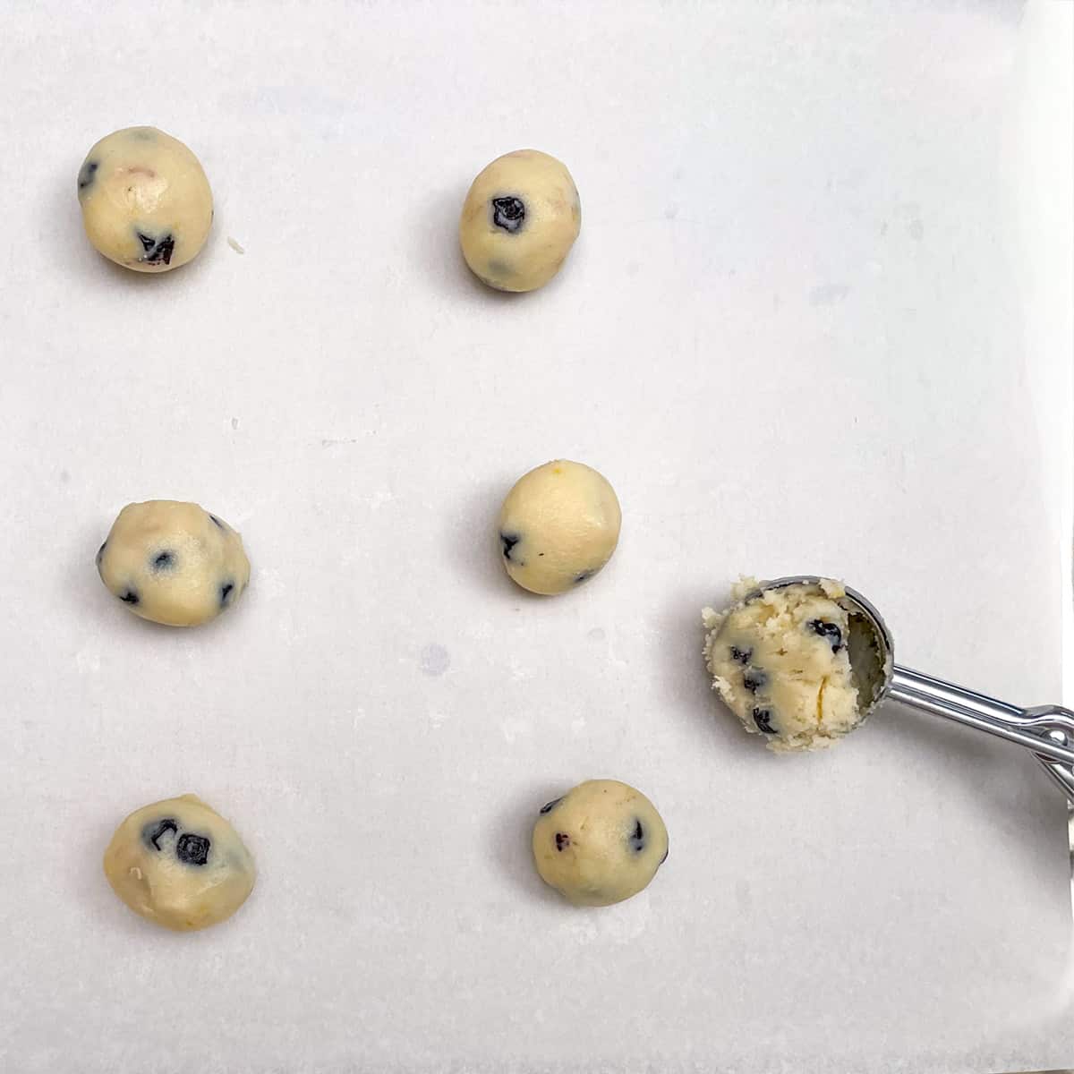 Making balls with a medium size cookie scooper on a parchment lined cookie sheet pan.