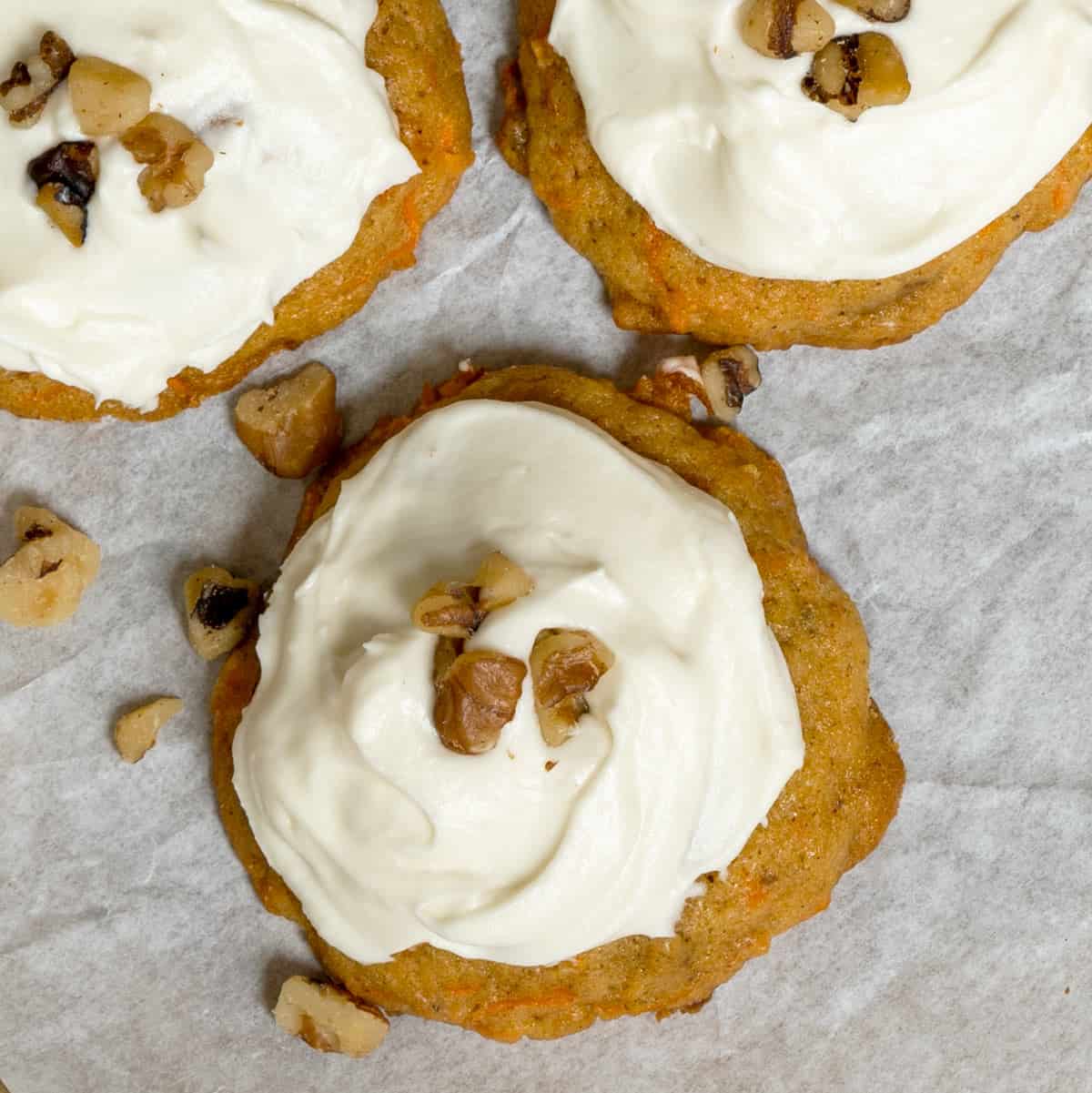 A top down look at carrot cake cookies with icing and chopped walnuts on top.