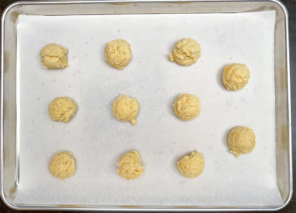 Cookie dough scooped onto parchment paper lined sheet pan.