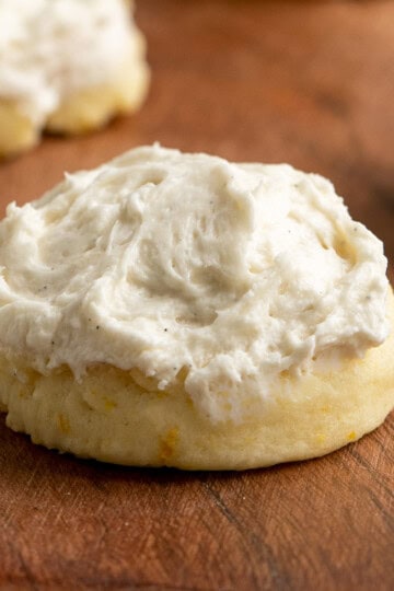 Orange cream cheese with vanilla bean icing cookie on a wooden plank.
