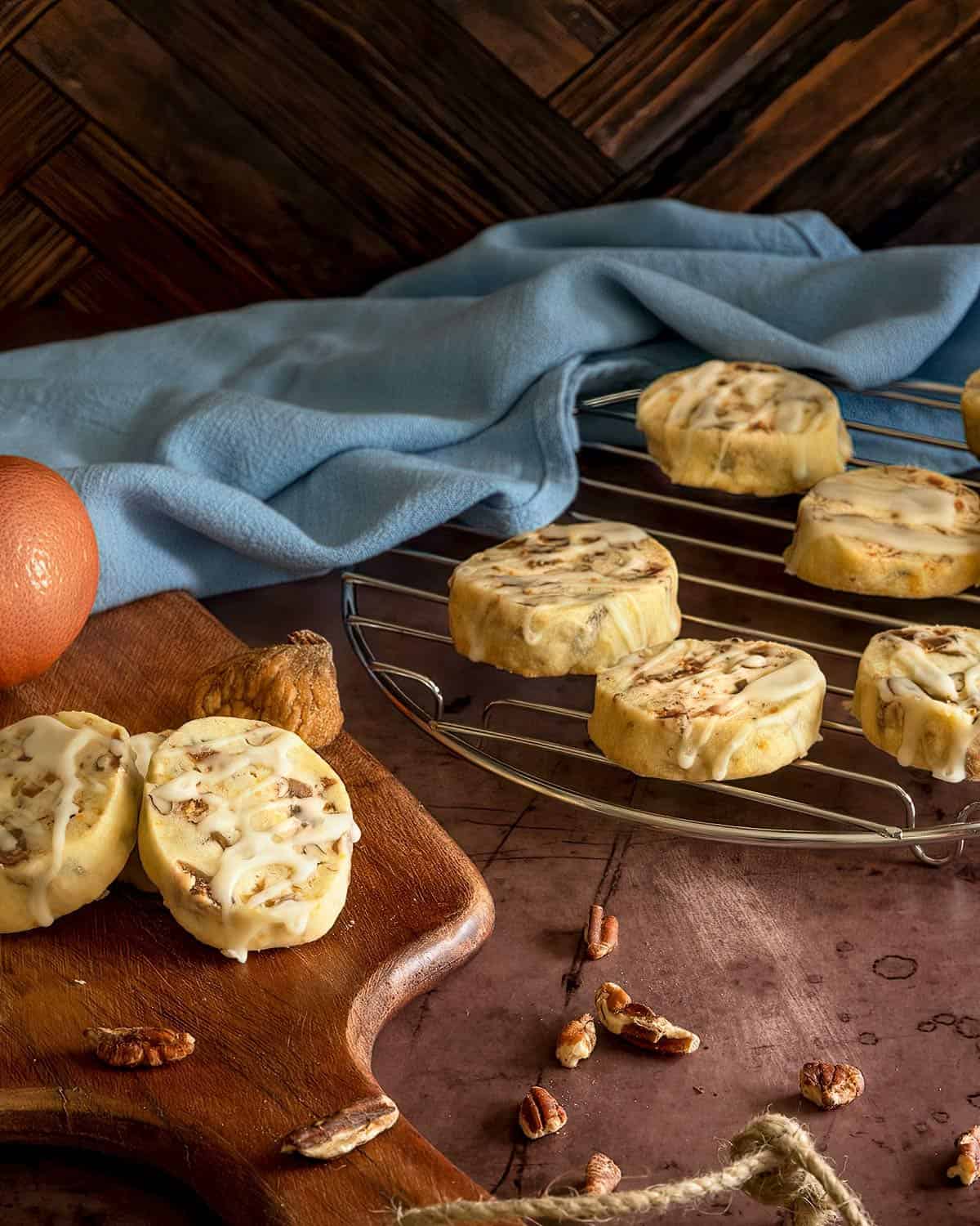 Fig pecan cookies with honey orange glaze displayed on a small cooling rack and a wooden board.