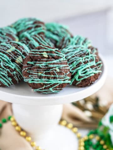 Finished double chocolate mint cookies on a white pedestal for St. Patrick's Day.
