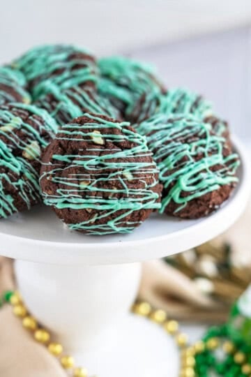 Finished double chocolate mint cookies on a white pedestal for St. Patrick's Day.