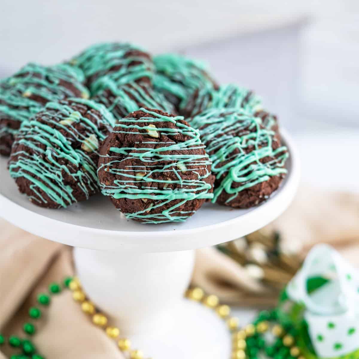 Finished double chocolate mint cookies on a white pedestal for St. Patrick's Day.