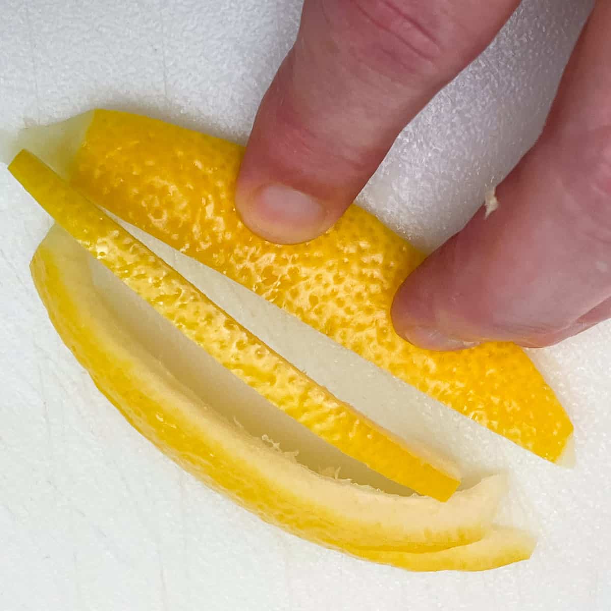 Cutting lemon peel into ¼ inch strips.
