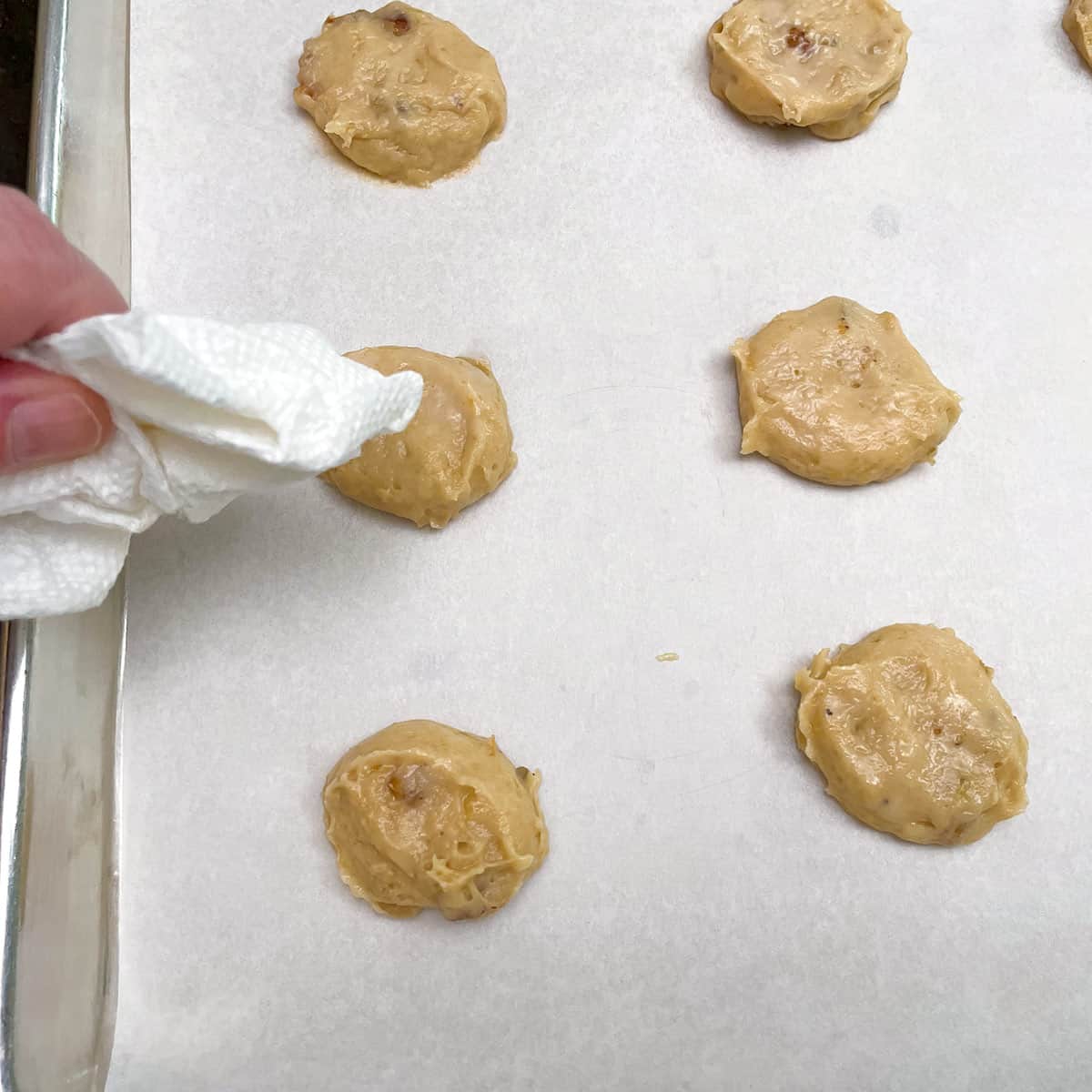 Dabbing the tops of the cookie mounds with a paper towel.