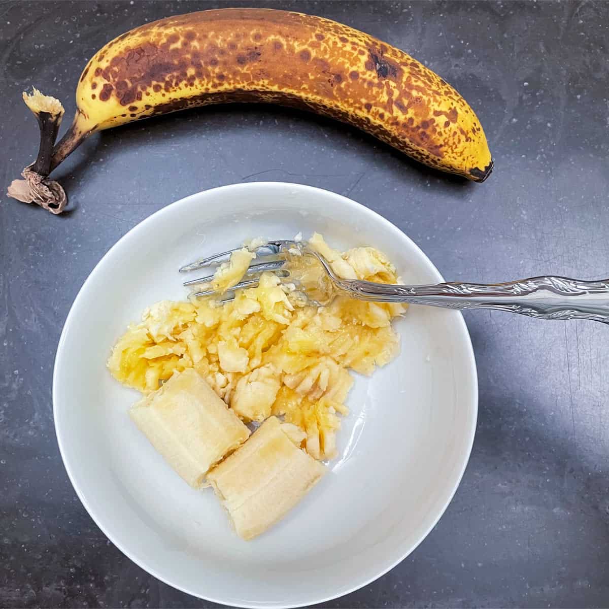 Smashing bananas with a fork in a bowl.