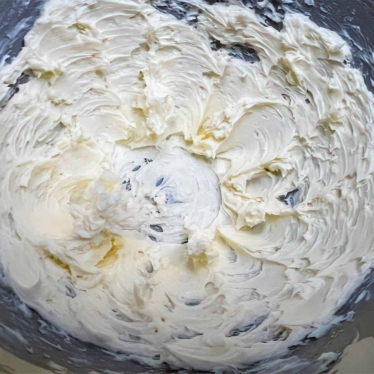 Creamed butter in a mixer bowl with creamy soft peaks.