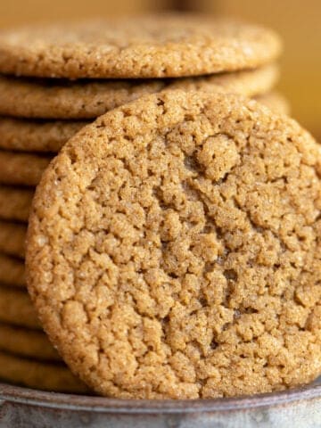 So good ginger cookies close up beside a stack of the cookies.