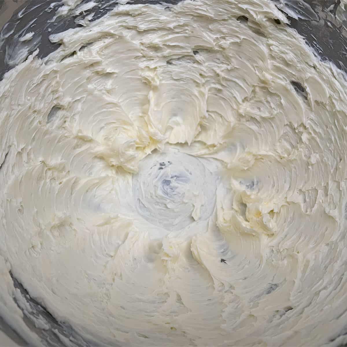 Mixer bowl with creamed butter looking like it is light and fluffy.