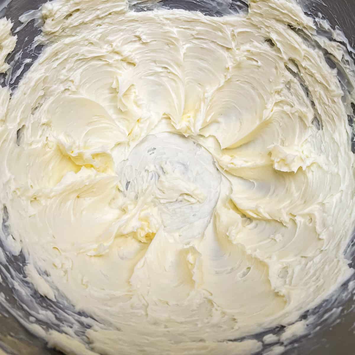 Creamed butter in a mixer bowl that has soft peaks along the sides of the bowl.