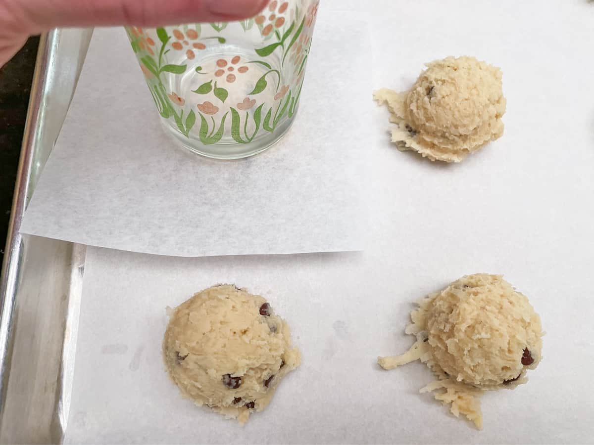 Using a square piece of parchment paper between the bottom of the glass and the cookie mound to flatten the top.