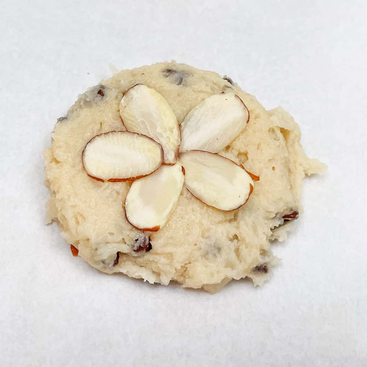 Five sliced almonds pieces place around in a flower pattern before baking the cookies.