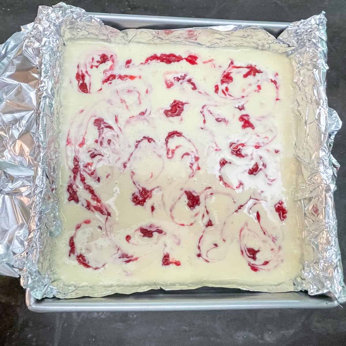 Raspberry jam swirled after the second round of dropping on the prebaked cheesecake.