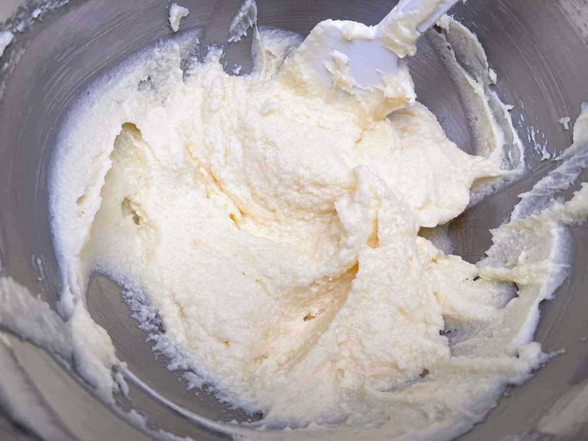 Mascarpone, sugar, and eggs mixed together in a mixer bowl.
