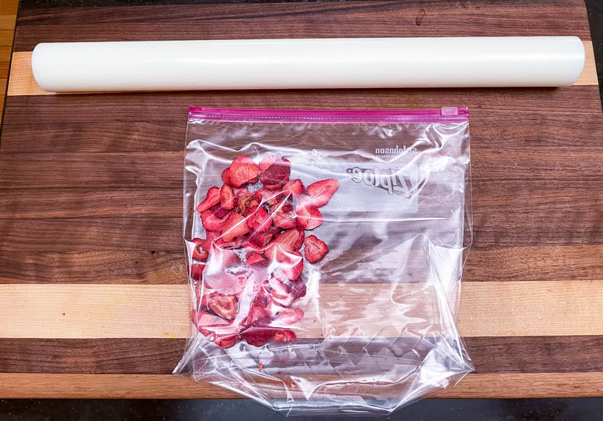 Freeze-dried strawberries added to a sealed plastic bag with a rolling pin to crush the strawberries.