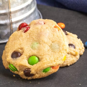 Close up of two peanut butter M&M cookies on a board.