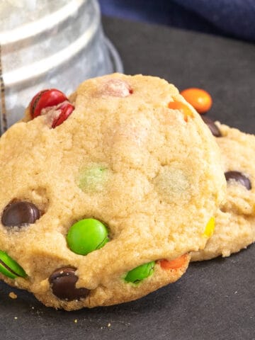 Close up of two peanut butter M&M cookies on a board.