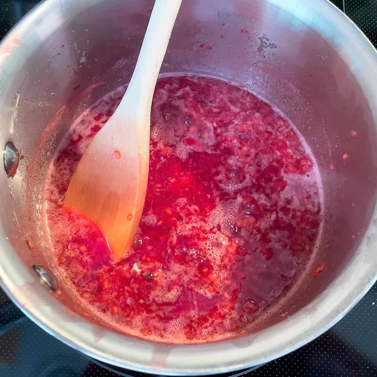 Raspberries on a low boil to break them up using the back of a wooden spoon.