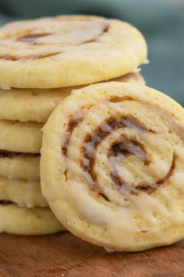 Close-up of a cinnamon orange pinwheel cookie with drizzles of icing zigged zagged across the top of the cookie.