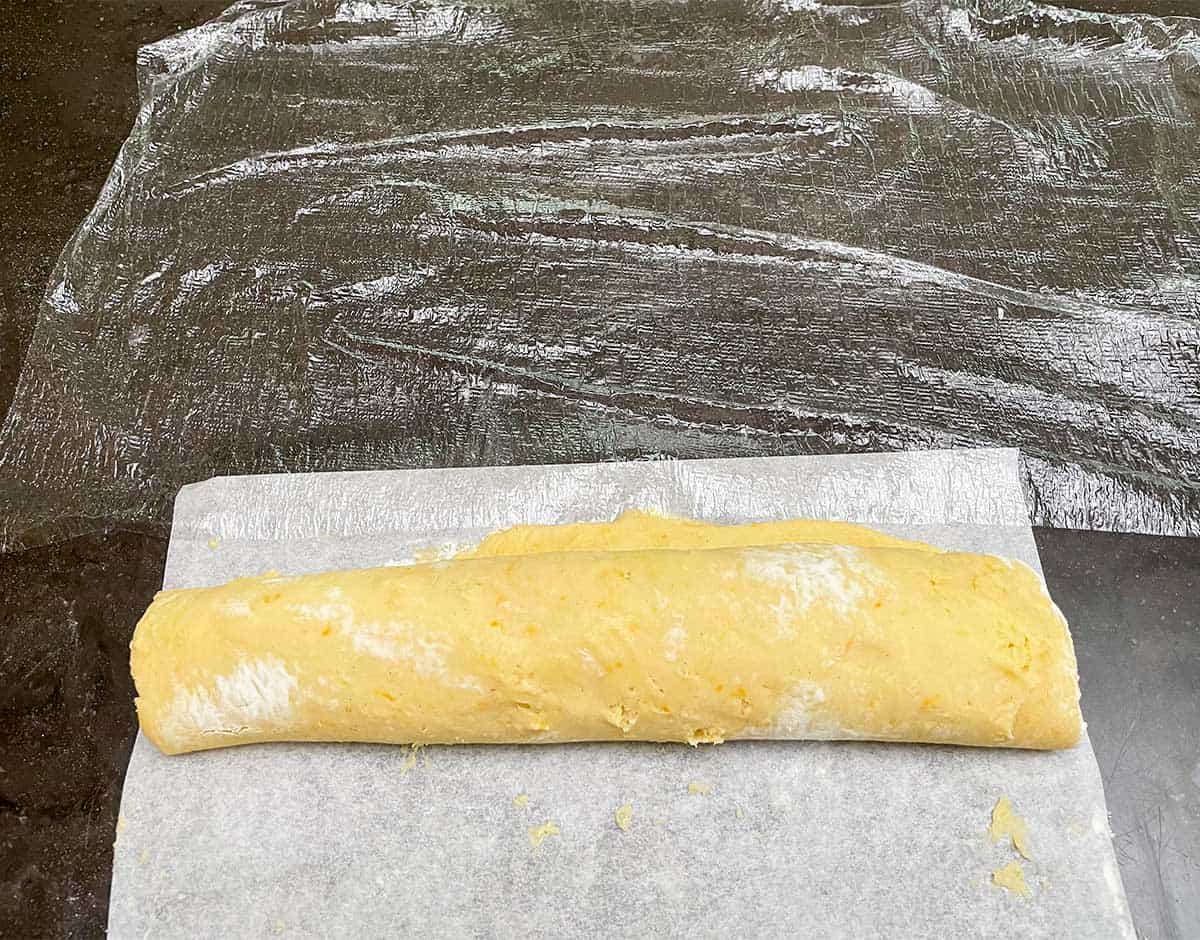 Cookie log being rolled onto plastic wrap.
