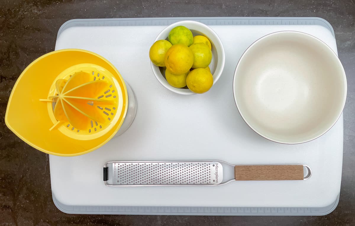 Cutting board with key limes, bowl and zester for zesting and reamer for gathering the juice.