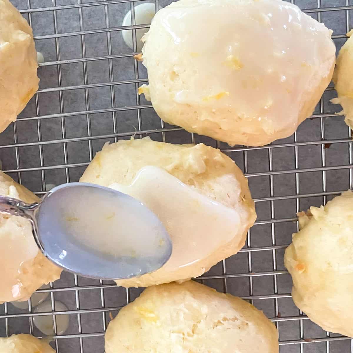 Spreading the lemon glaze on the top of a cookie.