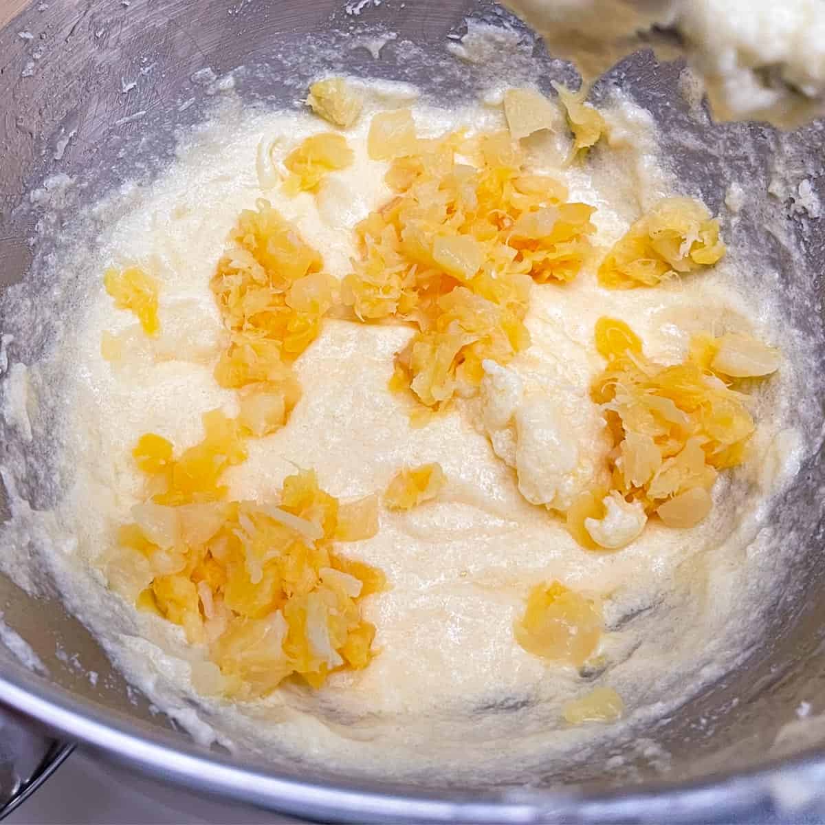 Adding the crushed pineapple that has been drained to the cookie dough.