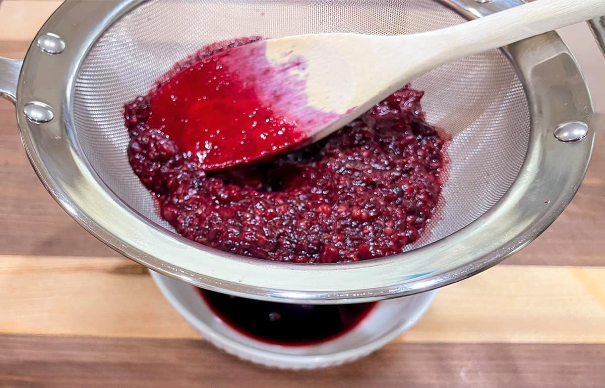 Cooked blackberries in a strainer to extract the blackberry juice.