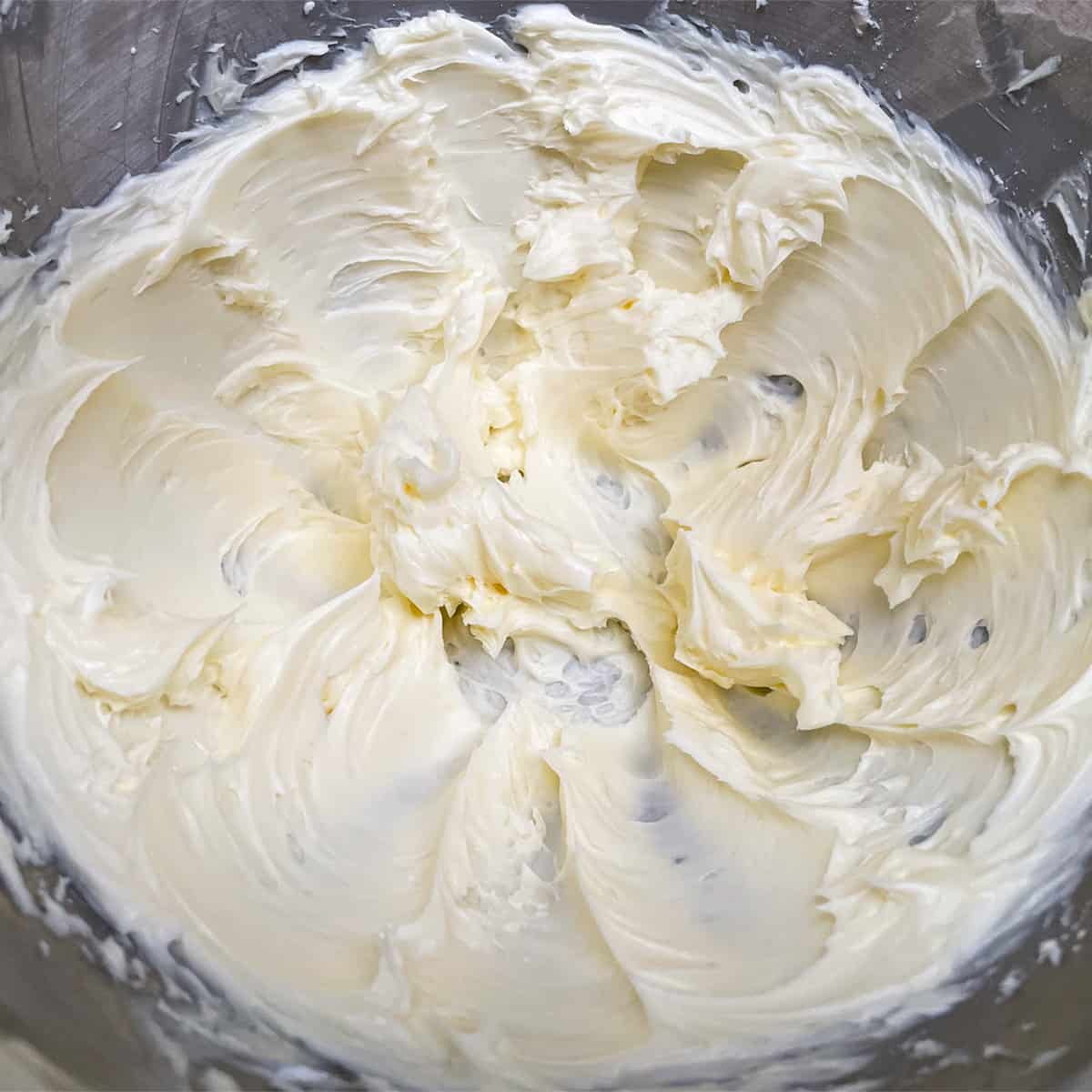 Creamy butter and sugar in a mixer bowl after a couple of minutes being mixed.