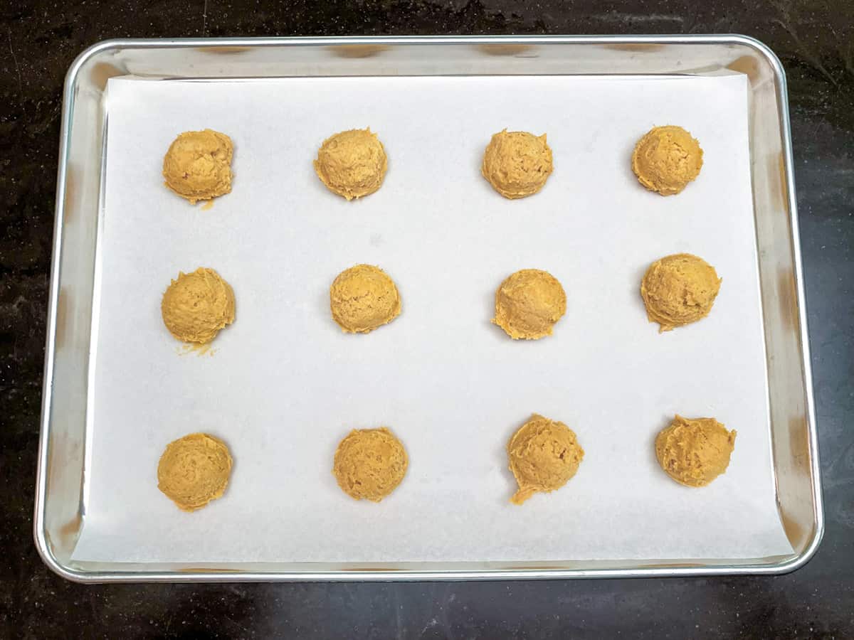 Twelve cookie scooped mounds on a parchment lined sheet pan.