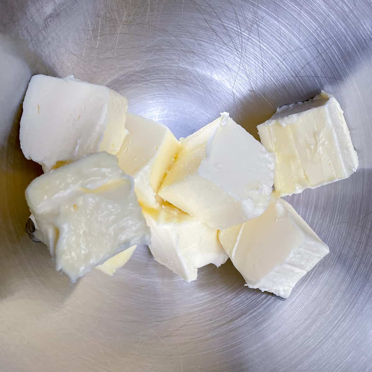Soft butter cut into cubes sitting in a mixer bowl.