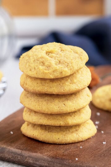 Stack of 5 baked Pumpkin Sugar Cookies on a wooden plank