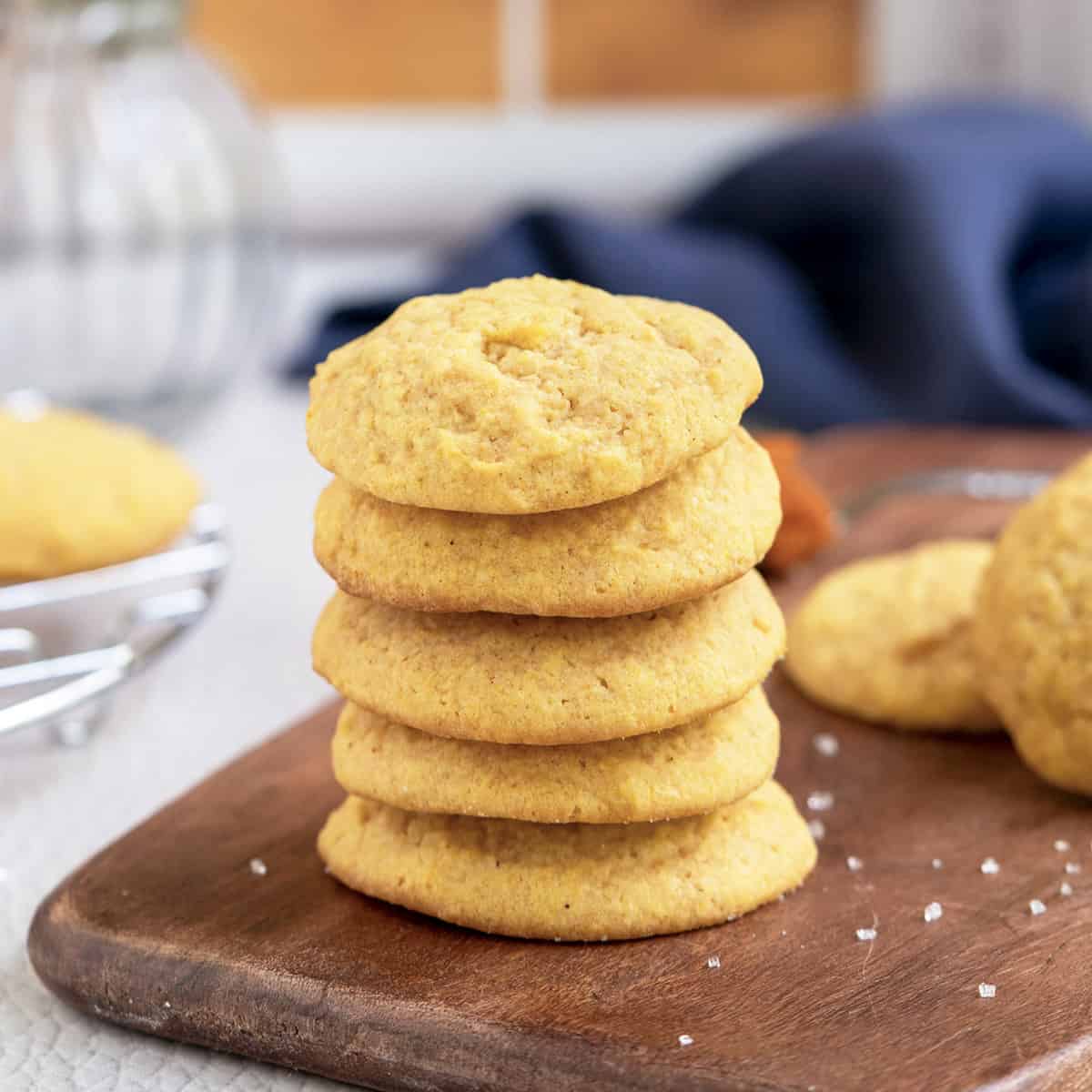 Stack of 5 baked Pumpkin Sugar Cookies on a wooden plank