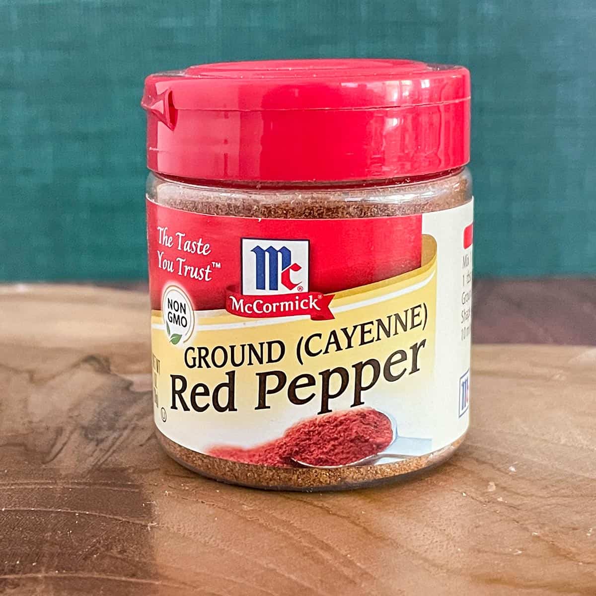 Jar of Ground Cayenne red pepper on a wooden slab.
