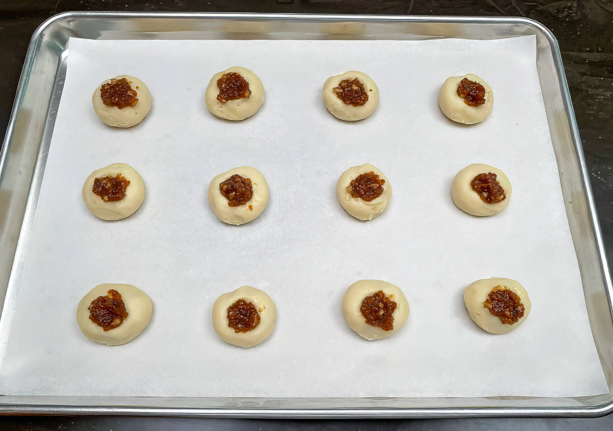 Twelve cookie balls that had thumbprint added and filled with fig and walnut filling.