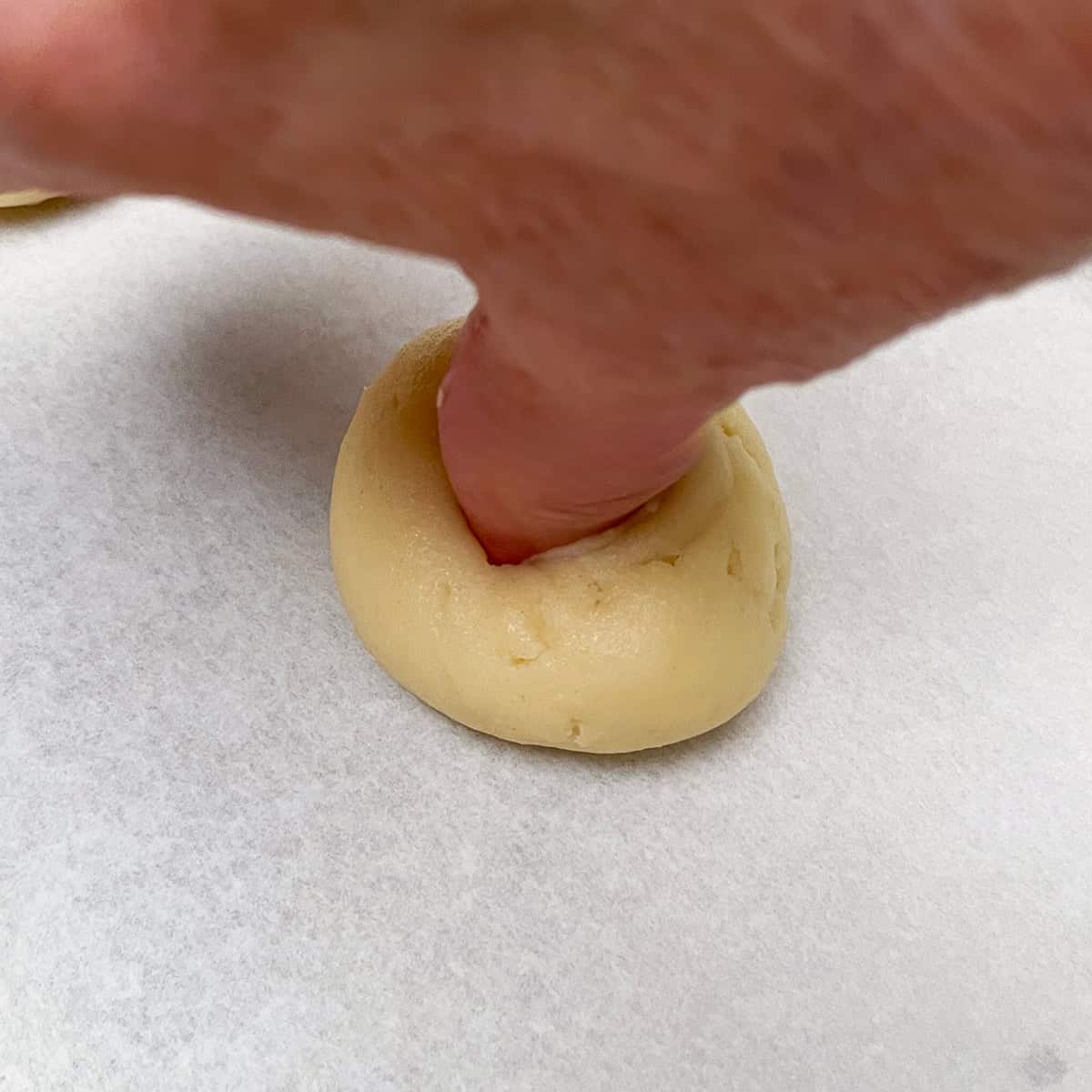 Using your thumb, I am showing how to make a well in the cookie dough ball.
