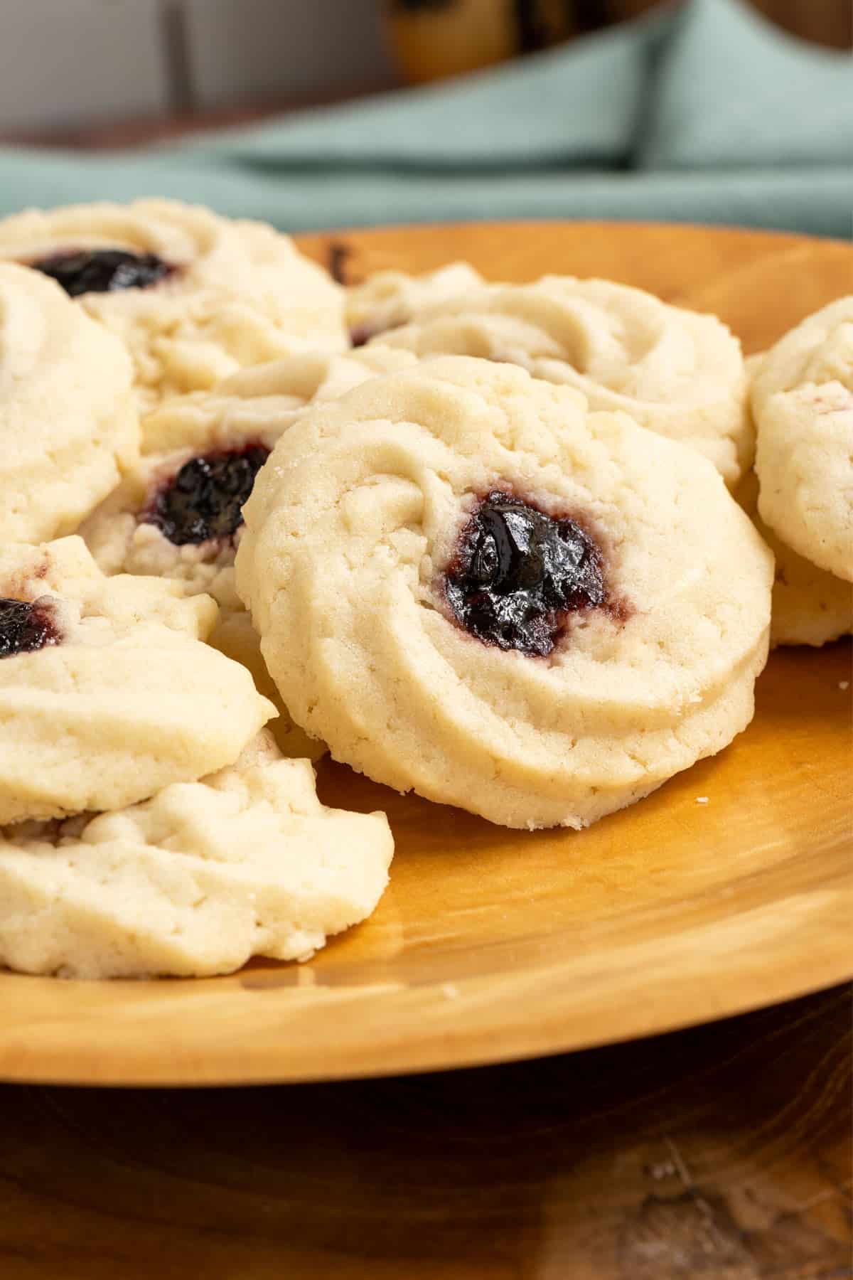 Close-up of the Shortbread cookies with jam on a wooden round plate.