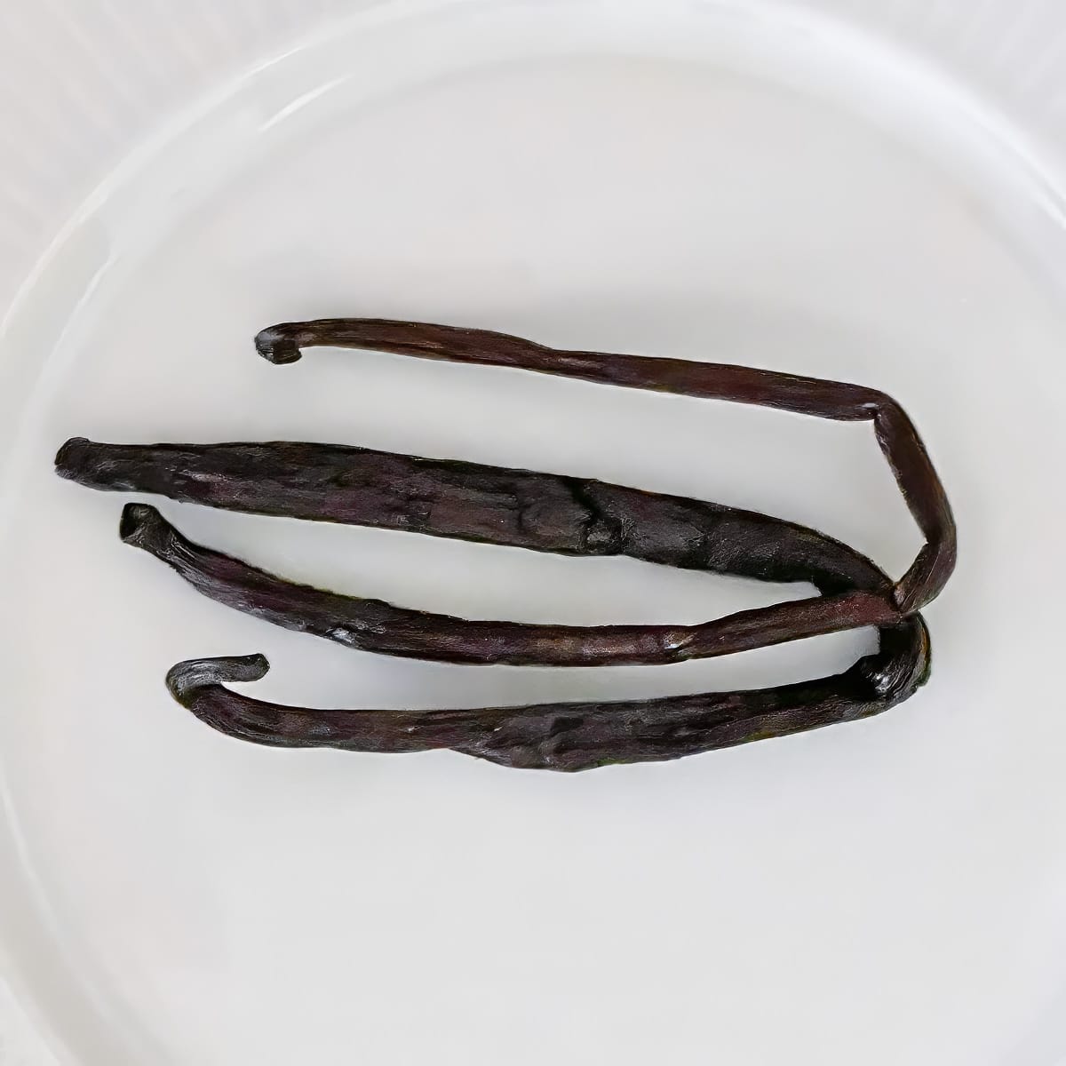 Two vanilla bean pods on a plate.